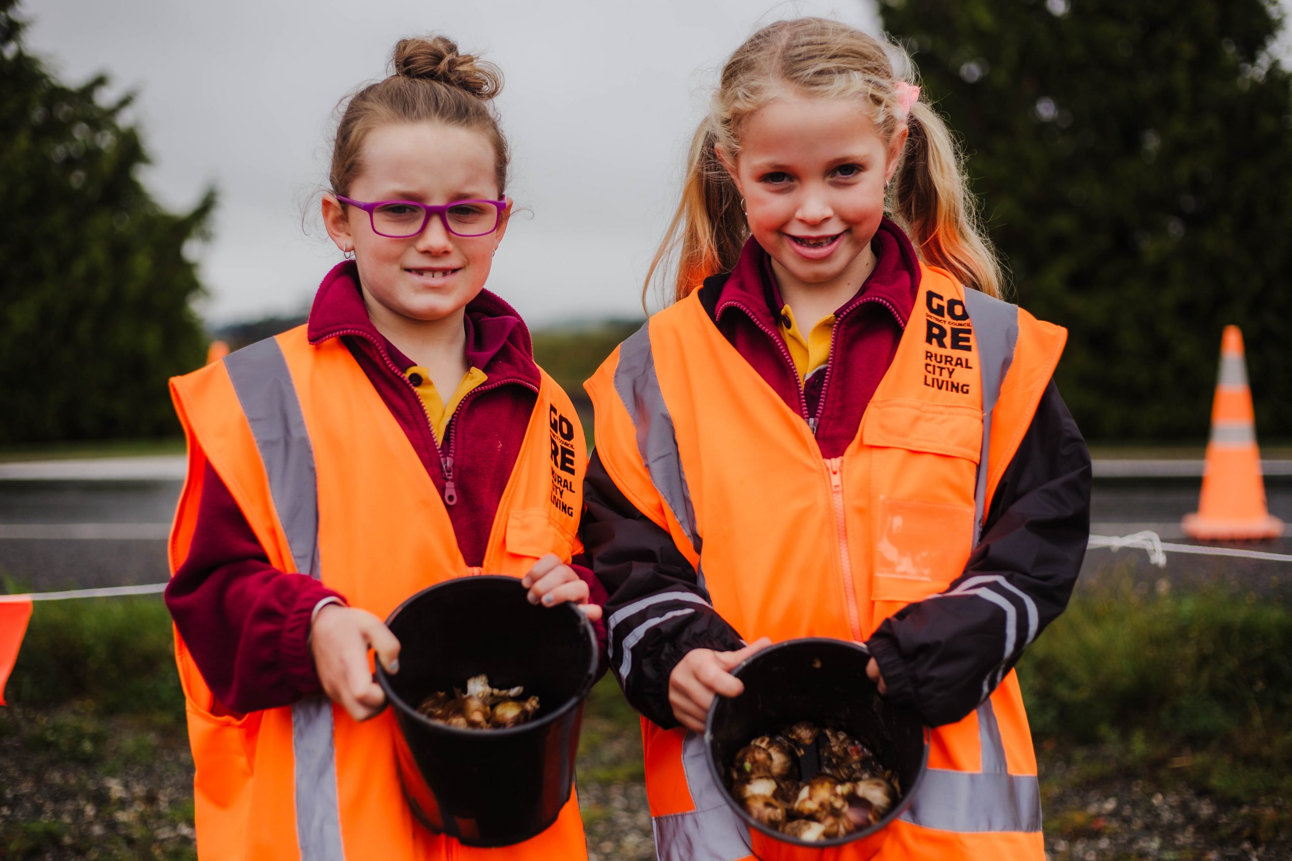 Two students holding bucket of daffodil seeds