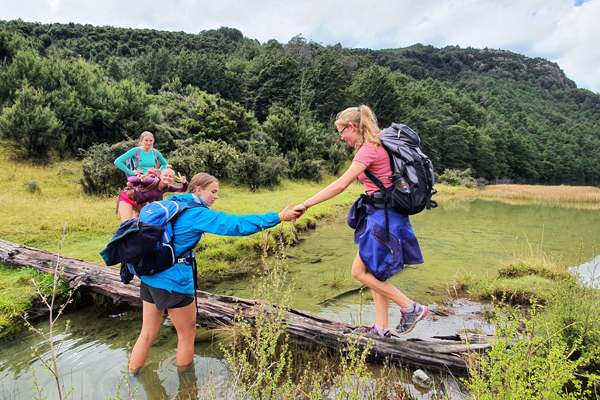 Girls helping each other cross river